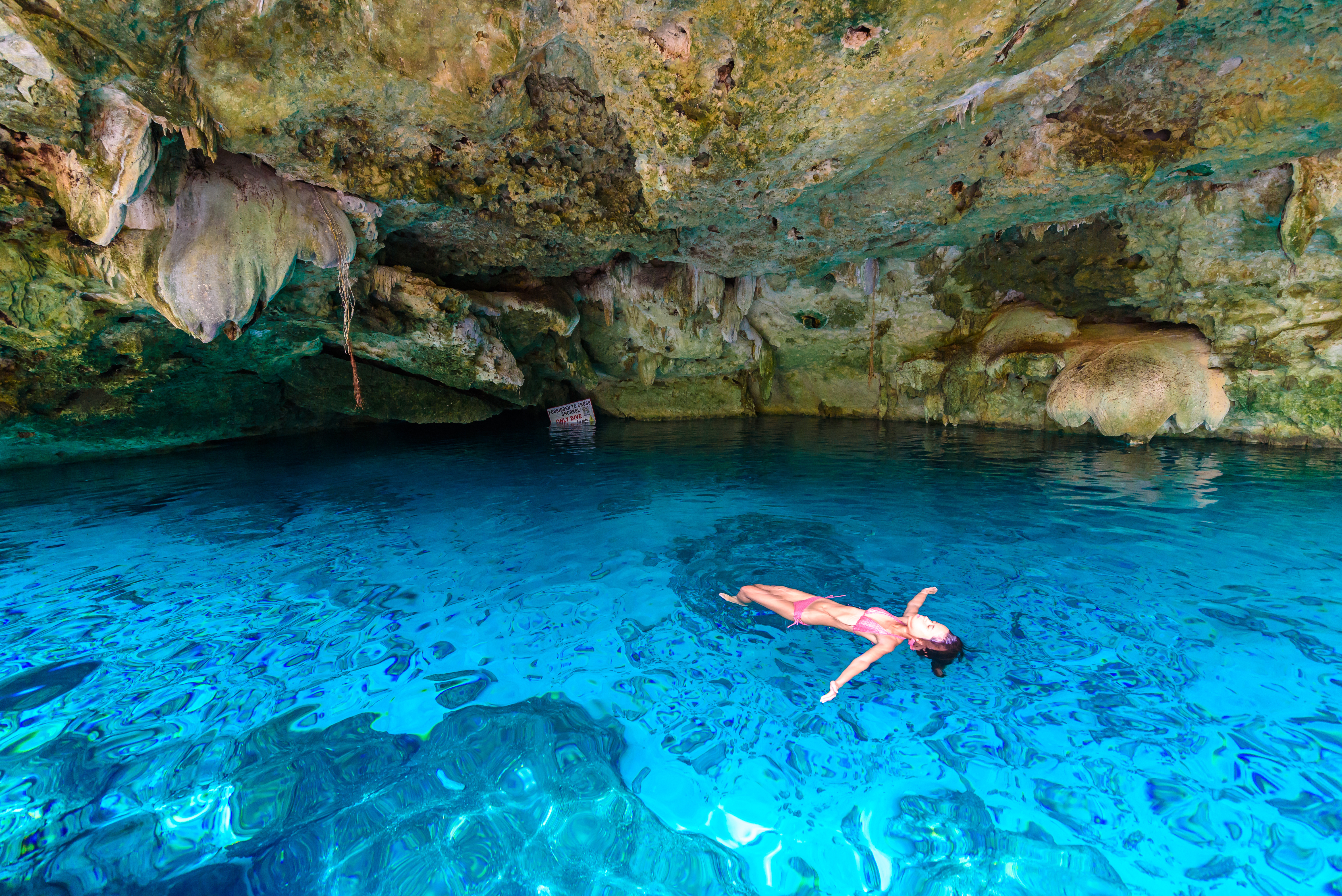 Frau liegt auf dem Wasser in einer Unterwasserhöhle